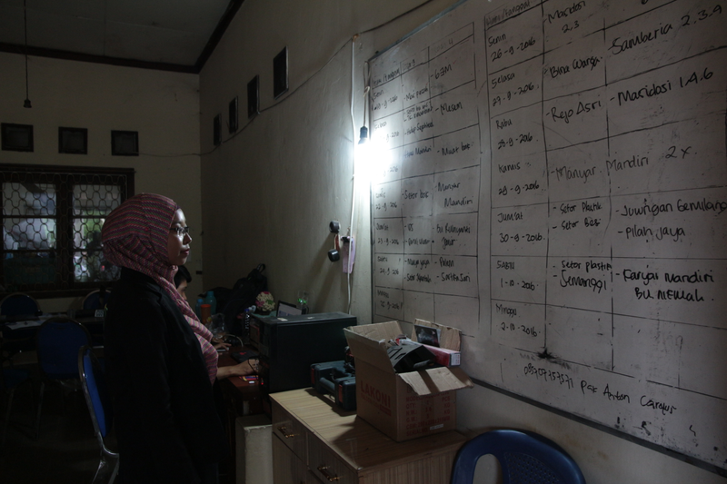 Trash Bank coordinator Ayu Andiri looks over the pickup schedule at Bank Bina Mandiri's offices.